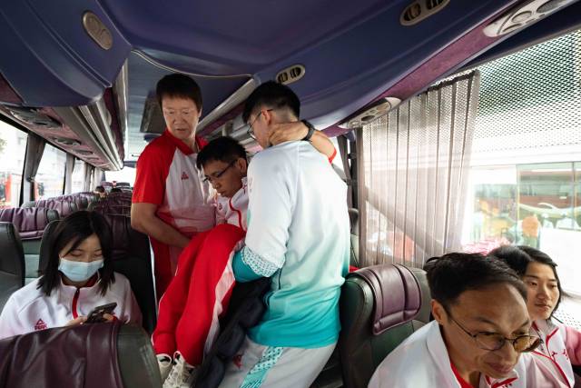出发前，助教张健忠将行动不便的队员们逐一抱上大巴。