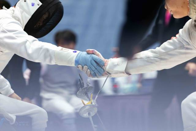 12月12日，在香港赛区男子花剑团体铜牌赛后，广东一团吴安迪（左）与对手握手。