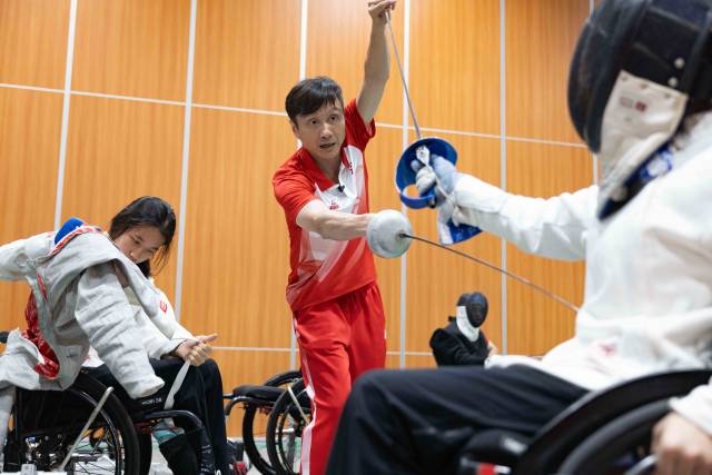 在训练基地中，龙杰正在手把手指导C级运动员出剑的位置。